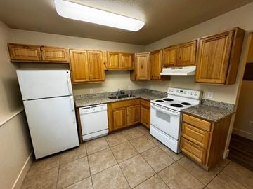 Wasilla apartment for rent - A kitchen with white appliances and wooden cabinets.