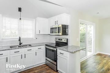 Concord house for rent - A kitchen with white cabinets and a granite countertop.