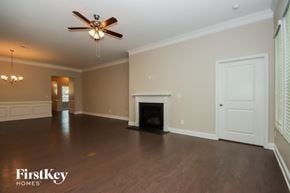 Denver house for rent - an empty living room with a fireplace and a ceiling fan
