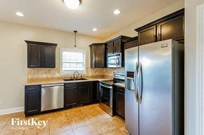 Clarksville house for rent - A kitchen with a refrigerator, sink, and cabinets.