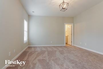 Jasper house for rent - a spacious living room with carpet and a door to the hallway