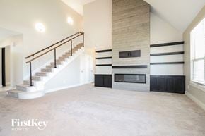 Yukon house for rent - a large empty living room with a staircase and a fireplace