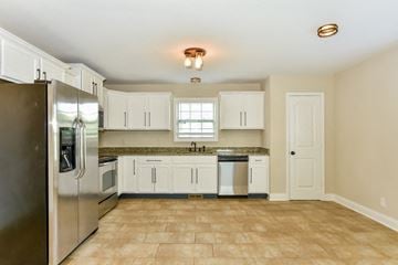 Clarksville house for rent - A kitchen with white cabinets and a tile floor.