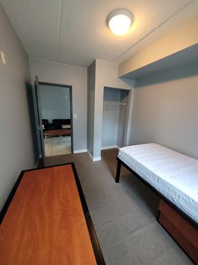 Waterloo apartment for rent - A bedroom with a bed, dresser, mirror and desk.