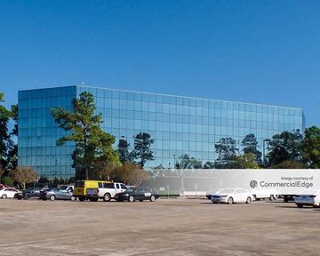 Houston apartment for rent - a large glass building with cars parked in front of it