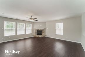 Charlotte house for rent - A spacious living room with a fireplace and a ceiling fan.