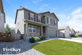 Lochbuie house for rent - a beige house with red shutters and a lawn