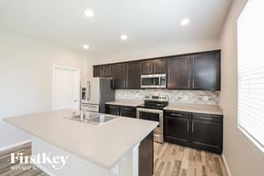 Lochbuie house for rent - a kitchen with black cabinets and a white counter top