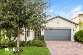 Alva house for rent - a house with a blue garage door and a driveway and trees
