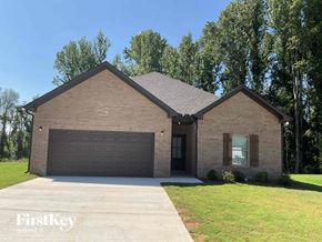 Clanton house for rent - A brick house with a garage door and a tree in the background.