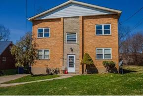 Cincinnati apartment for rent - a brick house with a white roof and a green lawn