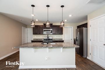 Dallas house for rent - A kitchen with a granite countertop and a refrigerator in the background.