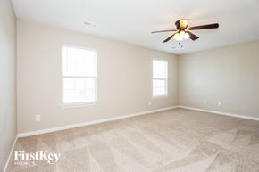 Dallas house for rent - A spacious room with a fan and two windows.