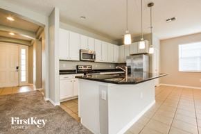 Kissimmee house for rent - a kitchen with white cabinets and a black counter top
