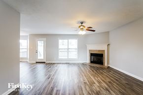 Clarksville house for rent - A spacious room with a fireplace and a ceiling fan.