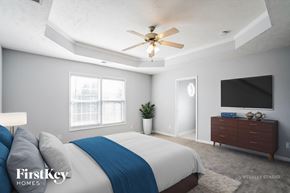 Clarksville house for rent - A bedroom with a bed, a ceiling fan, and a television.