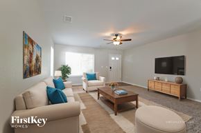 Denver house for rent - A living room with a beige couch, a wooden coffee table, and a flat-screen TV mounted on the wall.