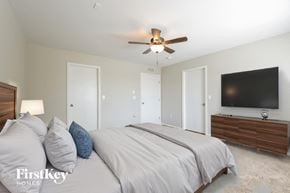 Denver house for rent - A bedroom with a bed, a ceiling fan, and a flat screen TV mounted on the wall.