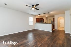 Fort Worth house for rent - an empty living room with a ceiling fan and a kitchen