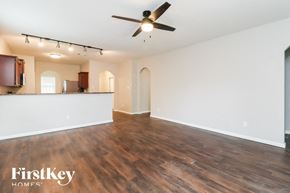 Fort Worth house for rent - an empty living room with a ceiling fan and a kitchen