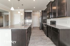 Adairsville house for rent - a kitchen with dark wood cabinets and granite counter tops and a sink