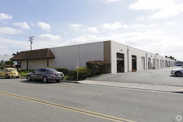 Huntington Beach apartment for rent - A grey building with a red roof is on the corner of a street.