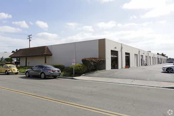 Huntington Beach apartment for rent - A grey building with a red roof is on the corner of a street.