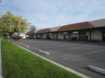 Huntington Beach apartment for rent - A parking lot in front of a building with a tree on the left.