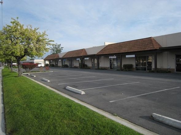 Huntington Beach apartment for rent - A parking lot in front of a building with a tree on the left.