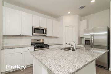 Saint Hedwig house for rent - a kitchen with white cabinets and a granite counter top