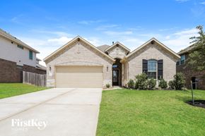 Conroe house for rent - a brick house with a garage door and a lawn
