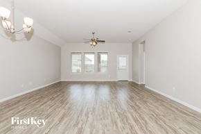 Conroe house for rent - an empty living room with a ceiling fan and a window