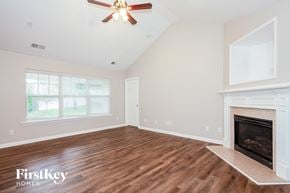 Charlotte house for rent - A spacious room with a fireplace and a ceiling fan.