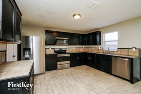 Mckinney house for rent - A kitchen with black cabinets and a tile floor.