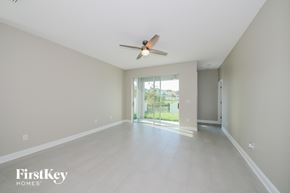 Bradenton house for rent - A spacious room with a ceiling fan and sliding glass doors leading to a balcony.