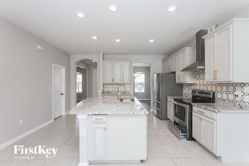 Parrish house for rent - A kitchen with white cabinets and a marble island.