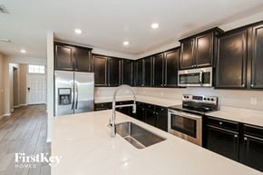 Jacksonville house for rent - a kitchen with black cabinets and white counter tops and a sink