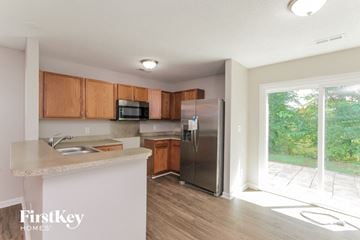 Mooresville house for rent - a kitchen with wood cabinets and a stainless steel refrigerator