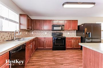 Waxahachie house for rent - a kitchen with wooden cabinets and black appliances