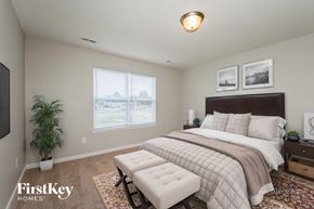 Wentzville house for rent - A bedroom with a large bed and a bench in front of it.
