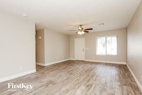 Peoria house for rent - A spacious room with wooden flooring and a ceiling fan.