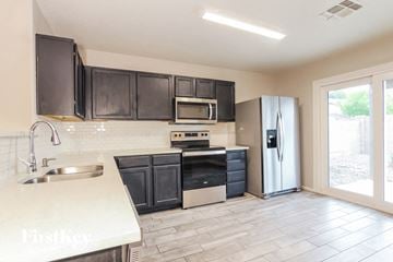 Peoria house for rent - A kitchen with black cabinets and a white sink.