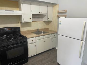 Gloucester City apartment for rent - A kitchen with a black stove top oven, white cabinets, and a white refrigerator.