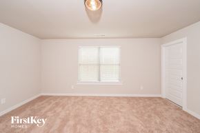 Odenville house for rent - A room with a carpeted floor, a window with blinds, and a door.