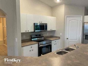 Cape Coral house for rent - A kitchen with a stove top oven and microwave built into the cabinetry.