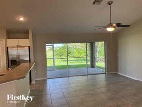 Cape Coral house for rent - A spacious kitchen and living room with a sliding glass door leading to a green outdoor area.