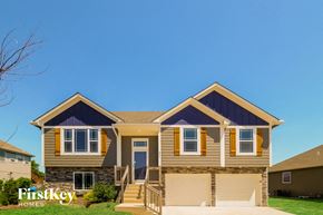 Raymore house for rent - a tan house with yellow trim and a blue sky