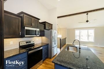 Raymore house for rent - a kitchen with black cabinets and stainless steel appliances