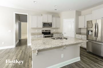 Statesville house for rent - a kitchen with white cabinets and a marble counter top