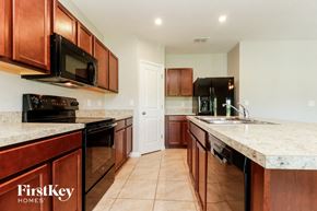 Winter Haven house for rent - a kitchen with wood cabinets and marble counter tops and black appliances